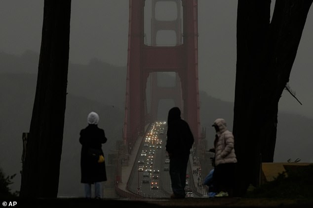 People look toward traffic on the Golden Gate Bridge from the Golden Gate Overlook in San Francisco as the storm rolls in