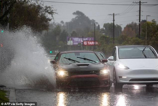 A car drives through a flooded road on La Cienega Boulevard in Los Angeles, California