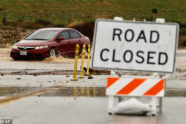 A driver goes though a road closed for flooding in Valencia, California
