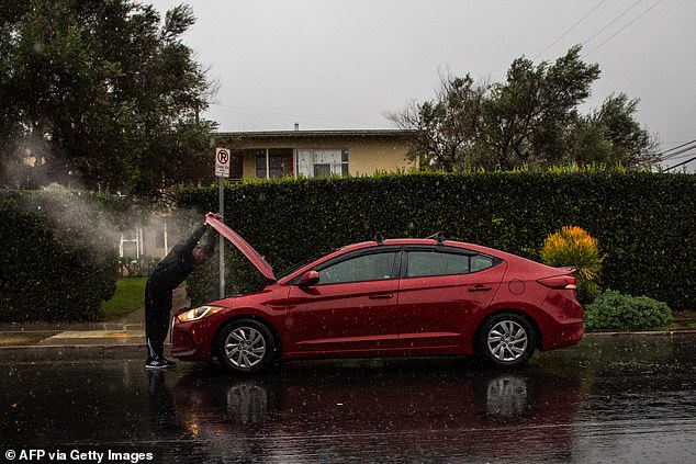 A man checks the damage caused by driving through a flooded road on La Cienega Boulevard o