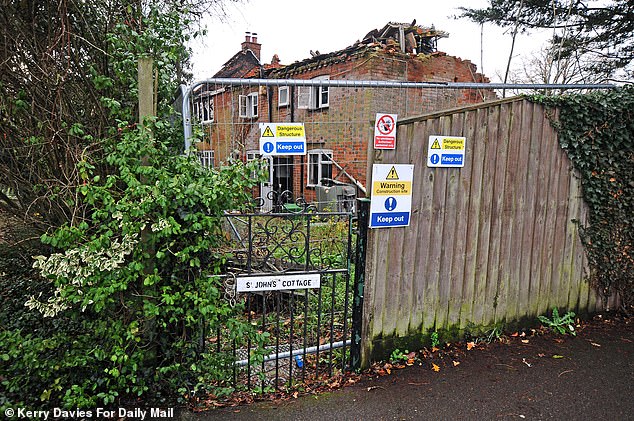 The cottage is currently closed off with metal railings and signs reading 'dangerous structure, keep out'