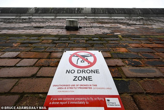 Pictured: A 'no drone zone' sign hangs on the outer wall of the Manchester prison