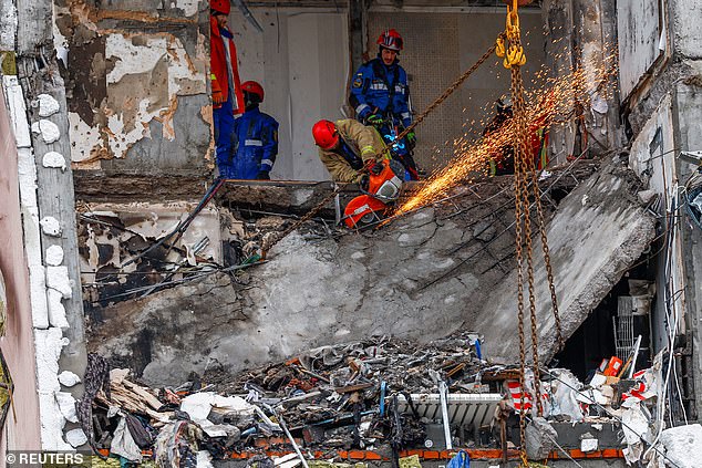 Rescuers work as they search for bodies at the site of an apartment building hit during Russian missile and drone strikes, amid Russia's attack on Ukraine in Kyiv, Ukraine December 27
