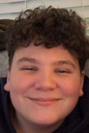 Headshot of Jay Black, a white 12-year-old boy with black curly hair, smiling.