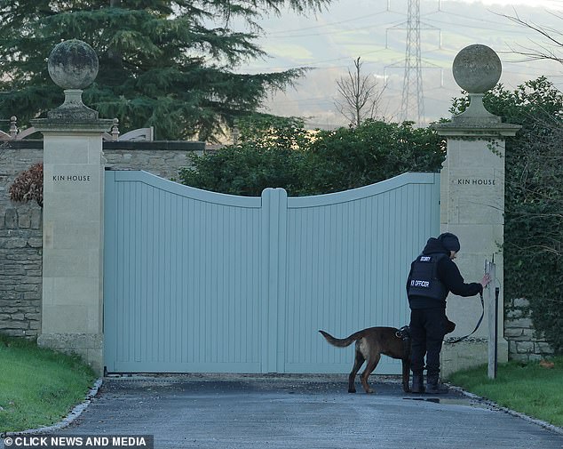 The security guard and the dog appear to be standing near a structure by the entrance of Kin House