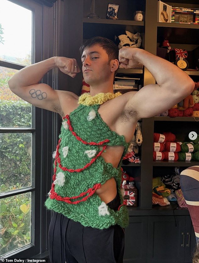 Retired Olympic diver Tom Daley, 31, got into the festive spirit as he flexed his muscles in a green Christmas tree vest, proudly showcasing another of his impressive knitted creations