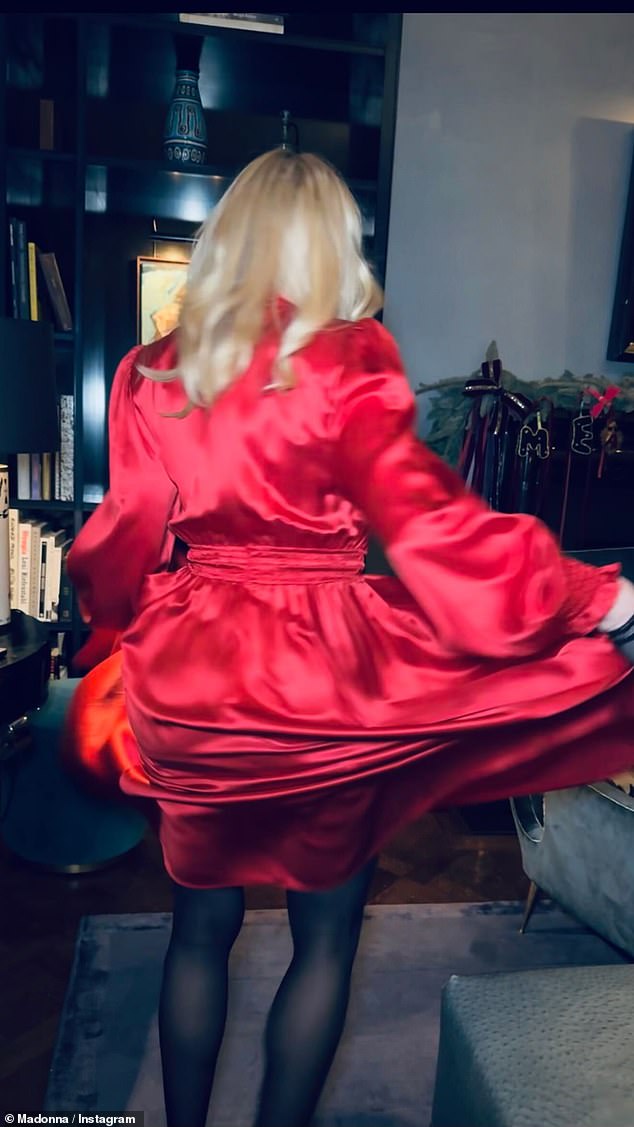 The Queen of Pop teamed the eye-catching ensemble, which featured a statement red bow at the bust and a cinched waist, with semi-sheer black tights as she danced around a living room