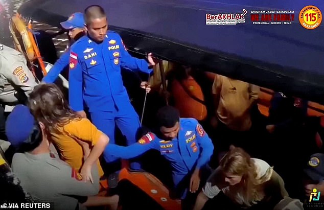 Rescue teams help survivors to shore after a boat carrying several people sank off the coast of Indonesia in extreme weather on Friday