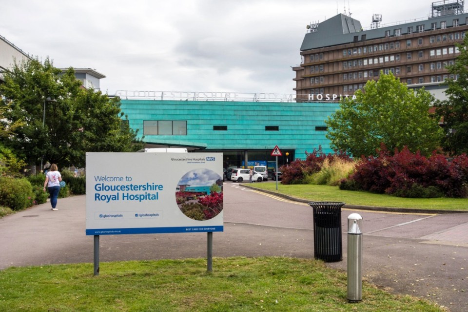 Gloucestershire Royal Hospital entrance sign with buildings in the background.