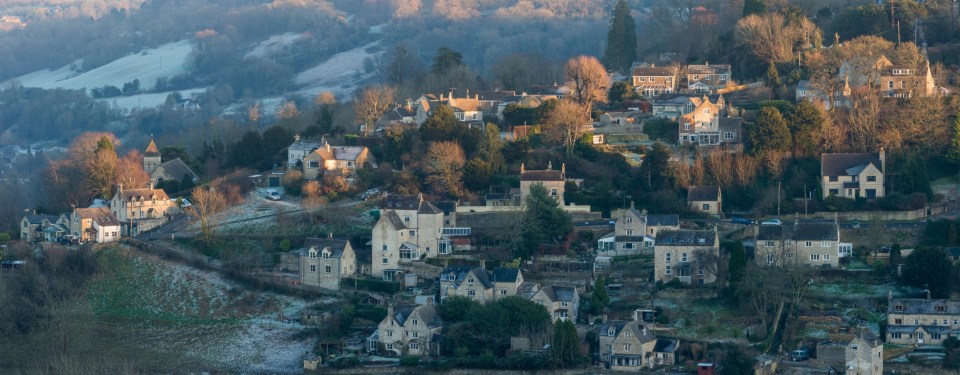 Houses scattered on a snowy hillside, with a church to the left.