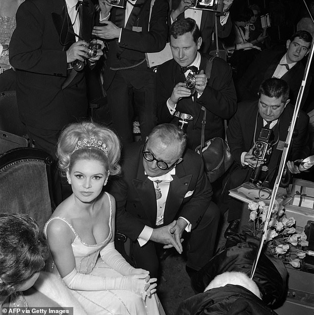 Brigitte Bardot and French Academician Marcel Achard flanked by photographers attend the French artists Union Gala event at the Cirque d'Hiver in Paris on March 9, 1962