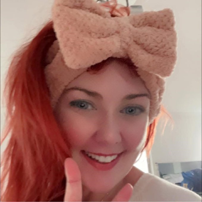 Jennifer Duncan, a woman with blue eyes and bright red hair, wearing a fuzzy pink bow headband.