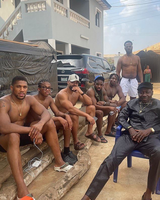 Joshua is pictured with his entourage in Nigeria at the beginning of this year, with the Lexus  involved in the crash in the background