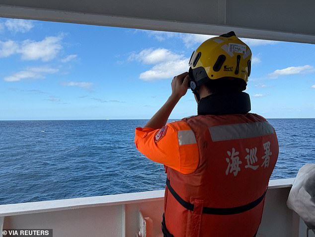 An officer on Taiwan Coast Guard patrol ship Yilan observes a Chinese Coast Guard vessel northwest of Pengjia islet, in this handout image released December 29, 2025