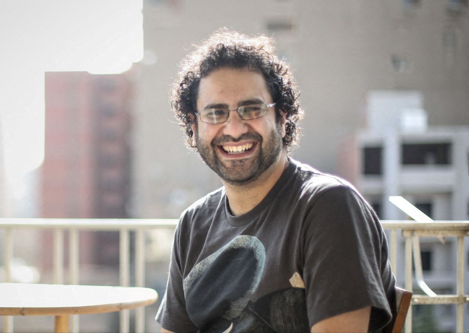 Activist Alaa Abd el-Fattah smiles while sitting outdoors.
