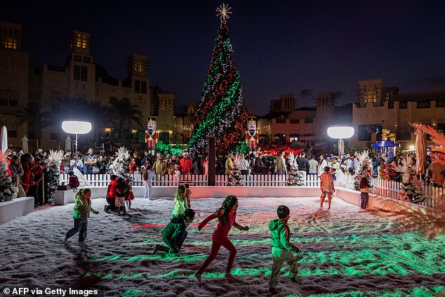 Children are pictured playing in a snow patch at a Christmas market in Souk Madinat Jumeirah in Dubai
