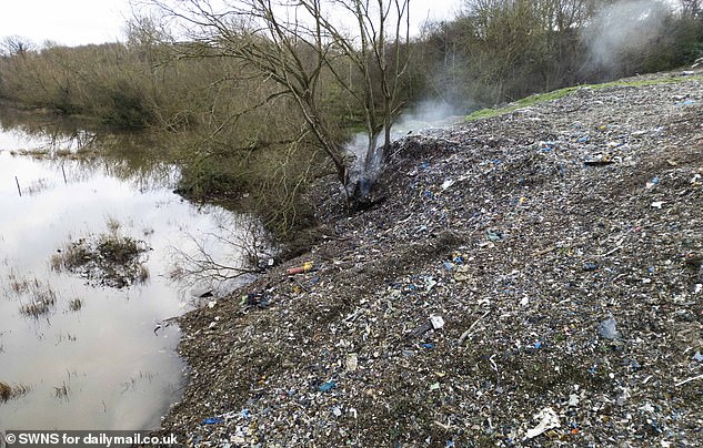 A smouldering pile of waste can be seen subsiding into the former Herefordshire and Gloucestershire Canal, which runs around the back of Over Farm in Gloucestershire