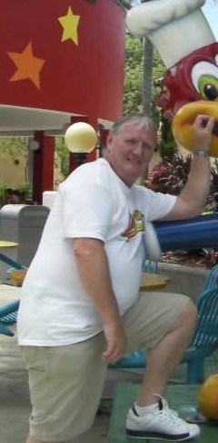 A man posing with a large cartoon chicken figure.