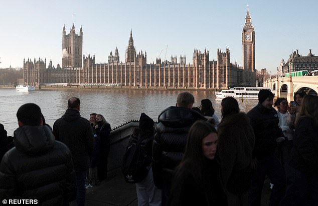 Visitors are pictured taking photos with the backdrop of the Houses of Parliament and Big Ben, which will chime in the new year