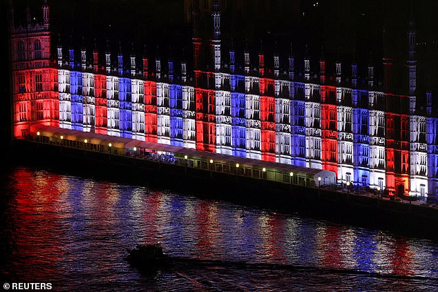 A boat sails in front of the illuminated Houses of Parliament, ahead of the Mayor of London's New Year's Eve fireworks