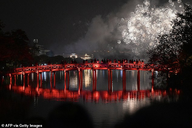 Partygoers watch fireworks explode of The Huc Bridge in Hanoi, Vietnam on December 21, 2025