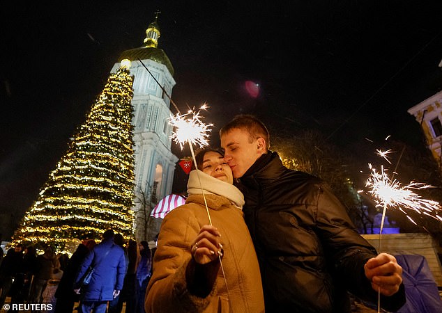 A couple kisses next to a Christmas tree during a New Year's eve celebration in Kyiv