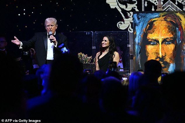 President Donald Trump (L) introduces a speed painter that created a Jesus art piece during the New Year's Eve Party