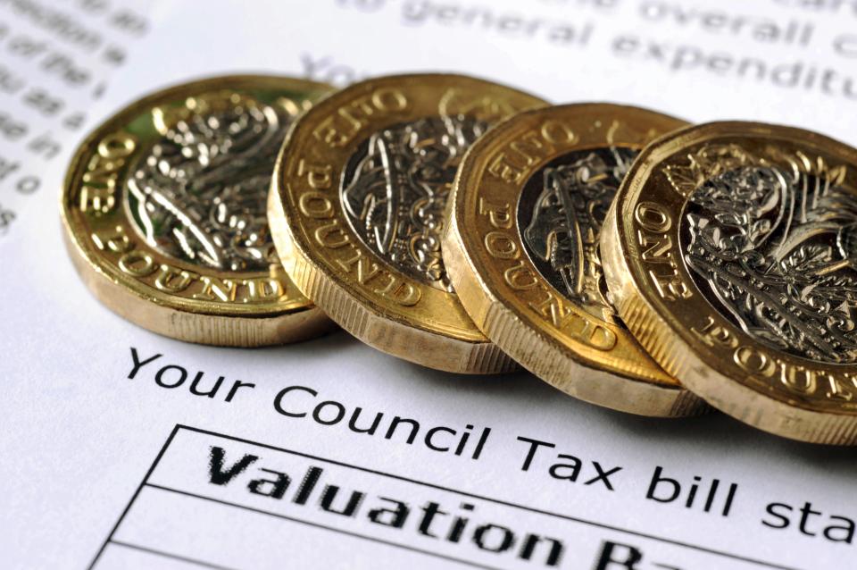 Four one-pound coins sitting on a council tax bill.