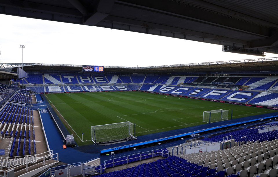 View of St Andrew's at Knighthead Park with empty blue and white seats and a green soccer field.