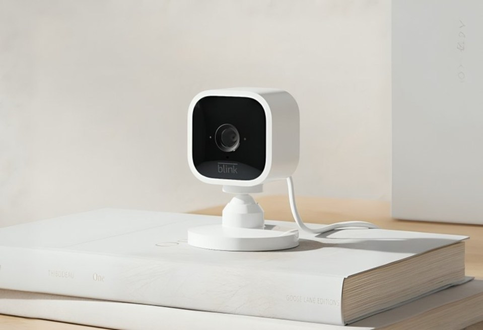 A white Blink Mini security camera on a white book.