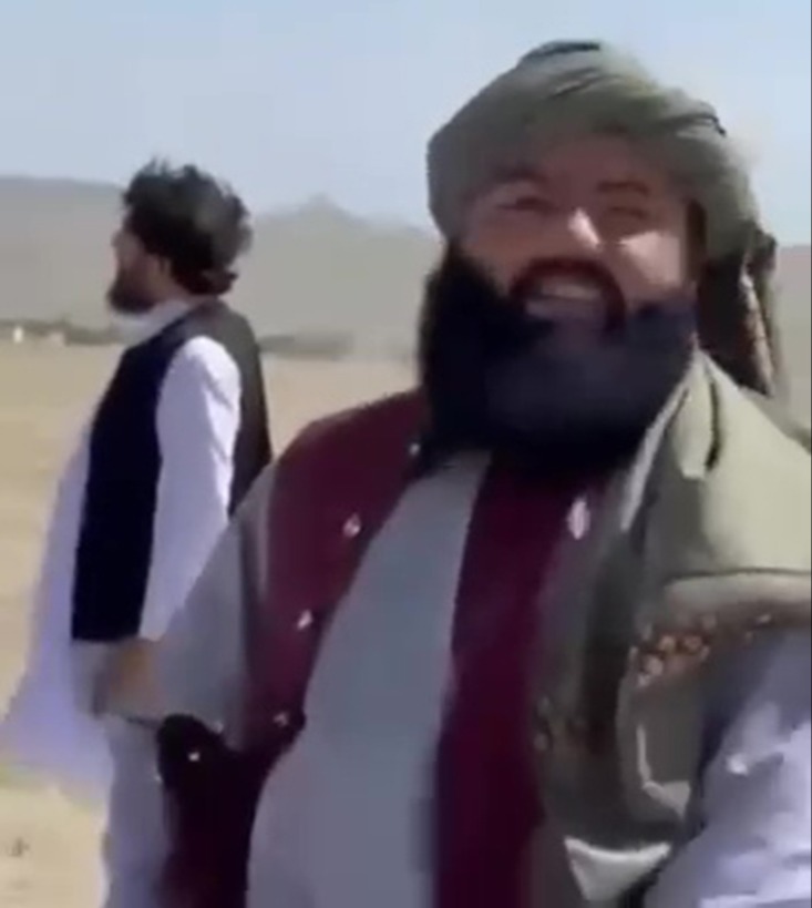 Azizrahman Azrawal in a desert-like setting, wearing a turban and traditional clothing.