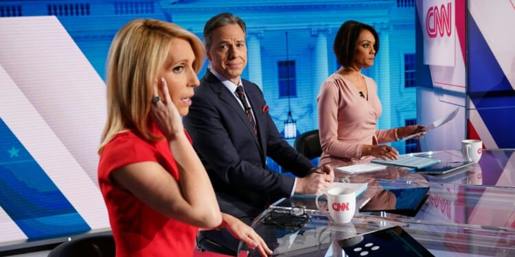 CNN news anchor Jake Tapper, flanked by Univision's news anchor Ilia Calderón, watches as co-anchor Dana Bash adjusts her ear piece before the start of the 11th Democratic Party 2020 presidential debate in a CNN Washington Bureau studio in Washington, D.C., on March 15, 2020.