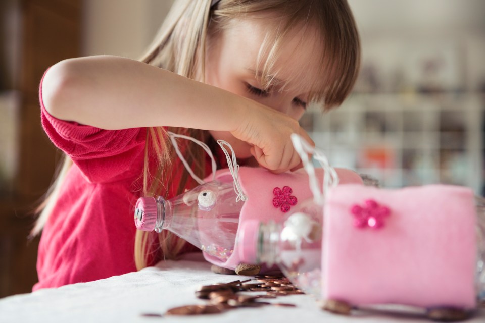 Girl inserting pocket money into a homemade piggy bank.