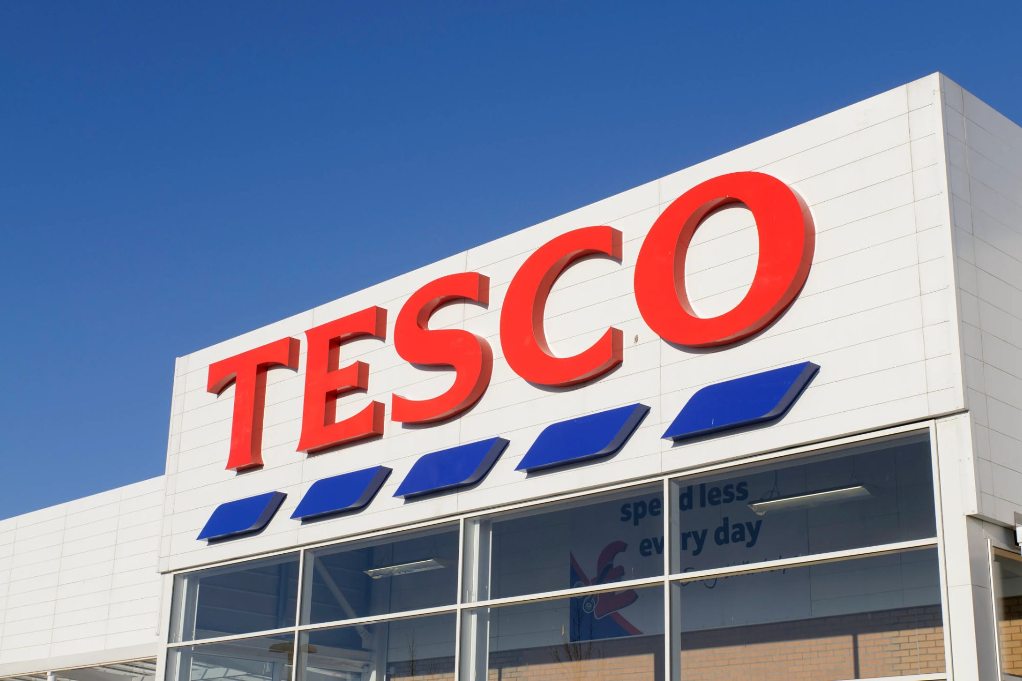An image collage containing 1 images, Image 1 shows Front entrance sign of a Tesco Superstore supermarket