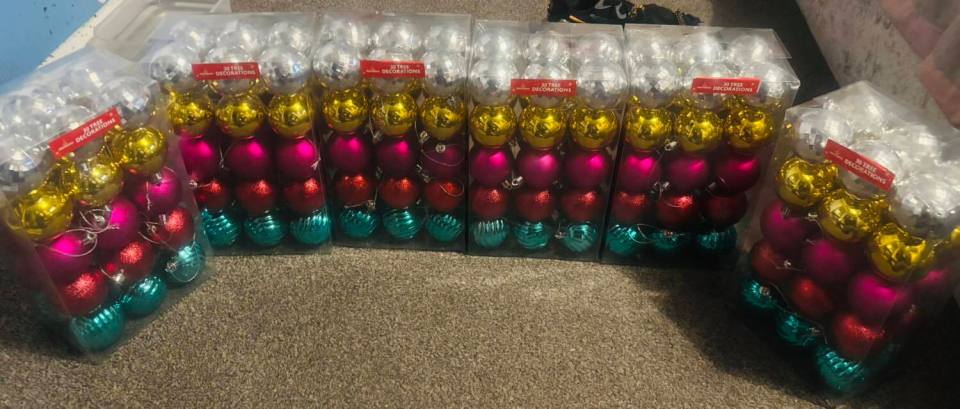 Numerous packages of Christmas tree decorations, including silver, gold, pink, red, and blue baubles.