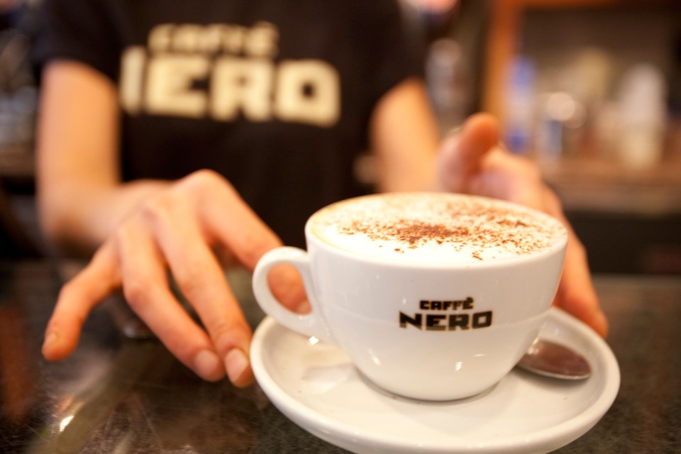 A Caffe Nero barista serving a cappuccino.
