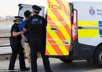 Police abandon investigations into almost four crimes every minute (stock photo of police officers escorting a man in handcuffs)