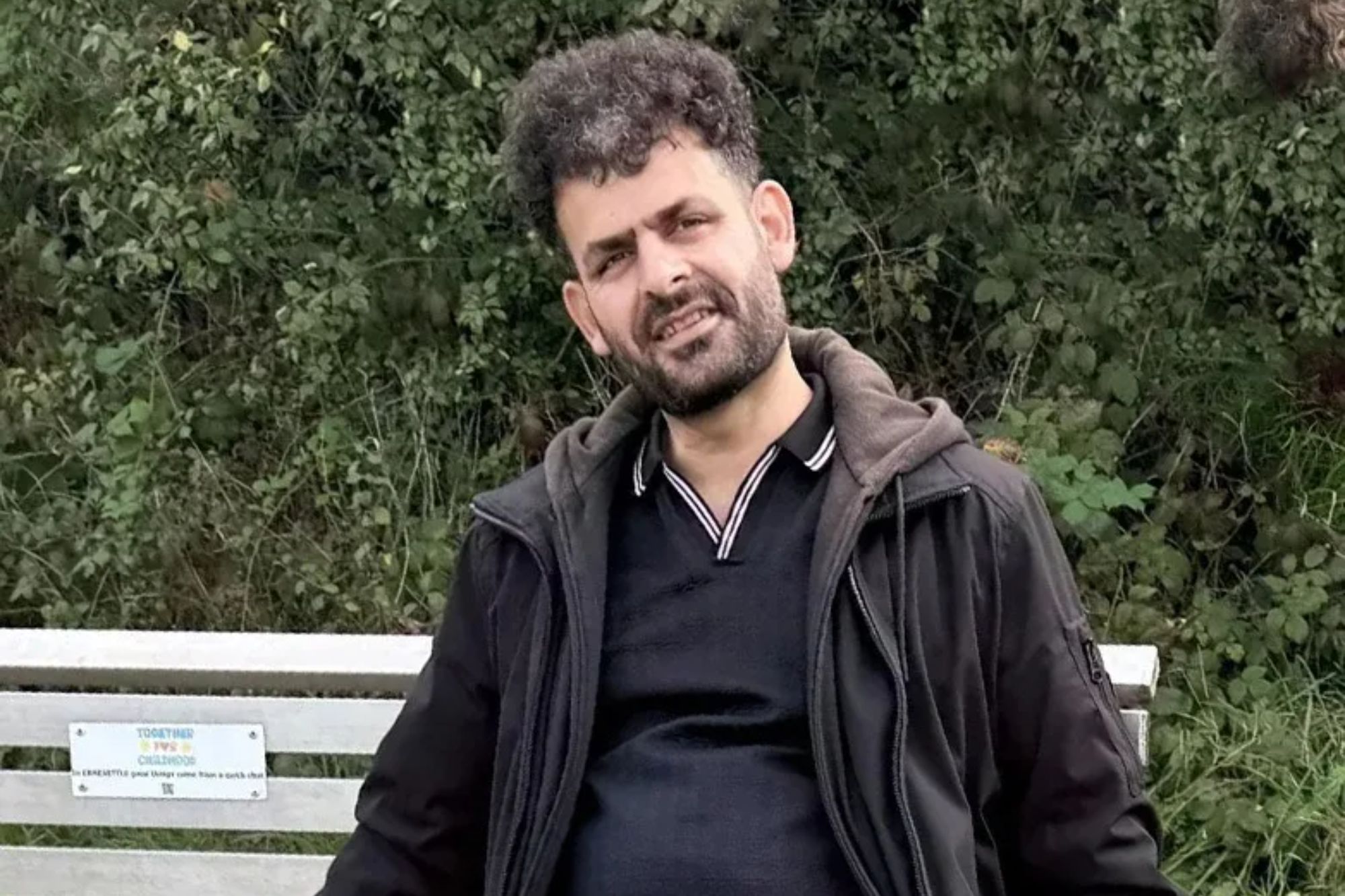 An image collage containing 1 images, Image 1 shows A man in a black jacket and blue jeans sitting on a park bench