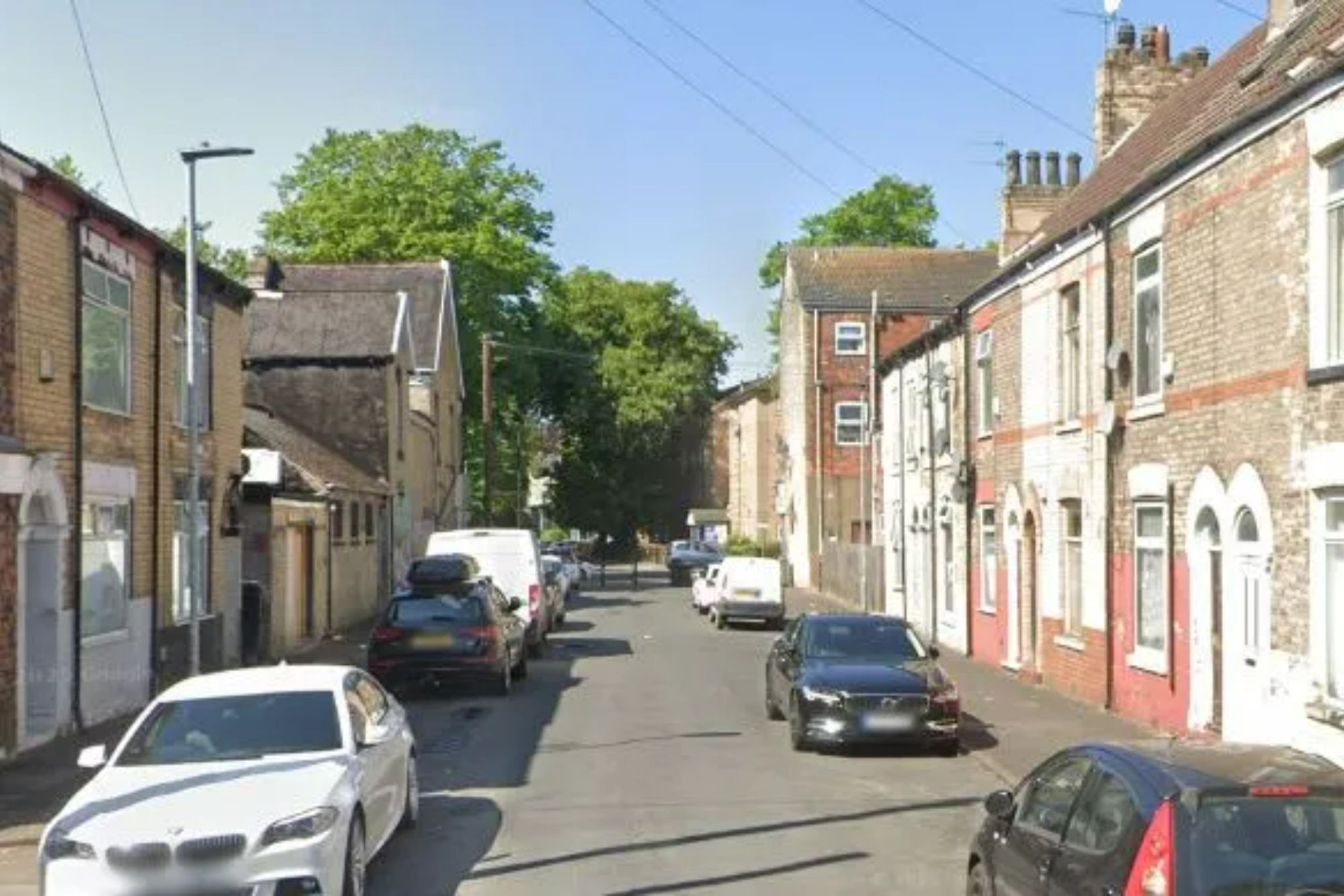 An image collage containing 1 images, Image 1 shows Street view of a residential road lined with cars and brick houses
