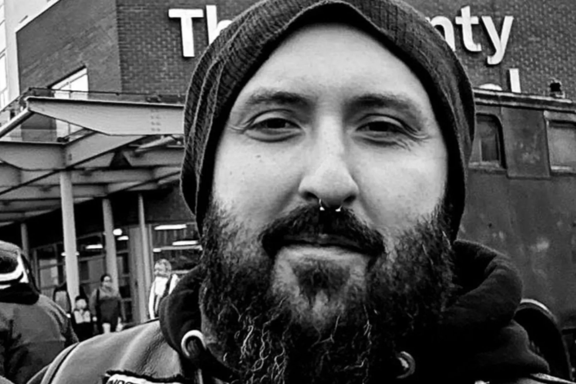 An image collage containing 1 images, Image 1 shows Black and white photo of Chris Bailey wearing a beanie and a nose ring