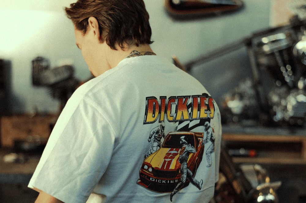 The back of a person wearing a white Dickies t-shirt with a racing car graphic.