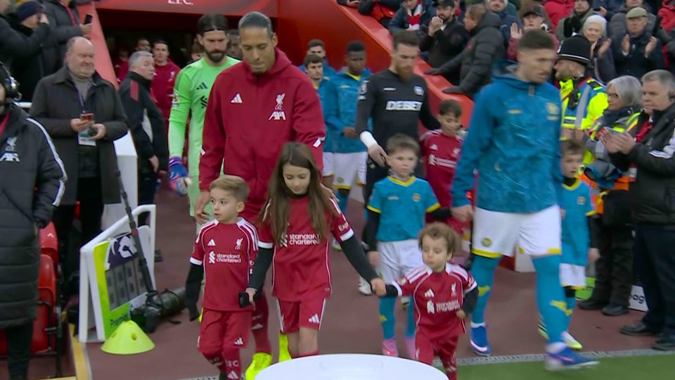 Liverpool FC players and mascots walking onto the pitch.