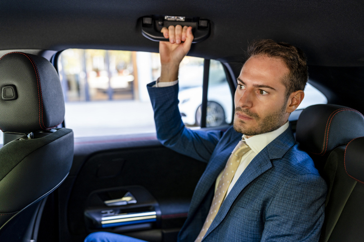 Businessman holding handle while sitting in a taxi.