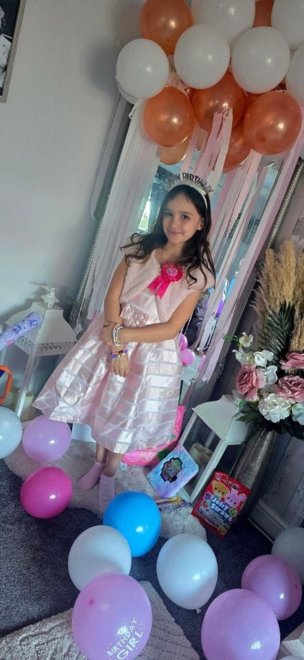 Nine-year-old Aria celebrating her birthday in a pink dress, surrounded by balloons and streamers.