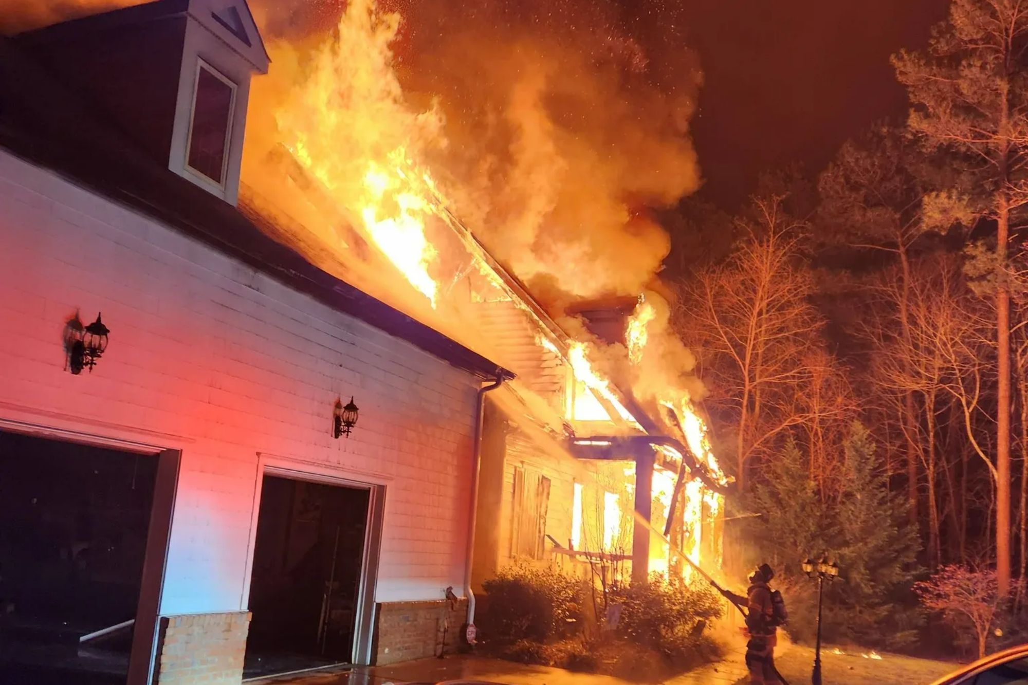 An image collage containing 1 images, Image 1 shows A house owned by NASCAR driver Denny Hamlin is engulfed in flames as a firefighter sprays water at the burning structure