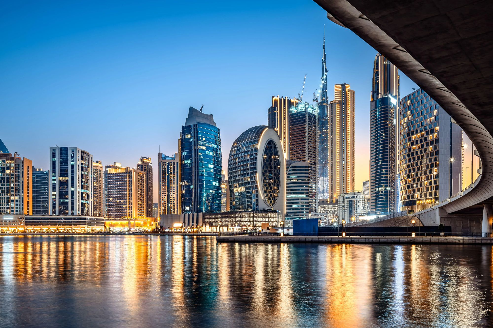An image collage containing 1 images, Image 1 shows The illuminated skyscrapers of Dubai's Business Bay reflect on the water at night