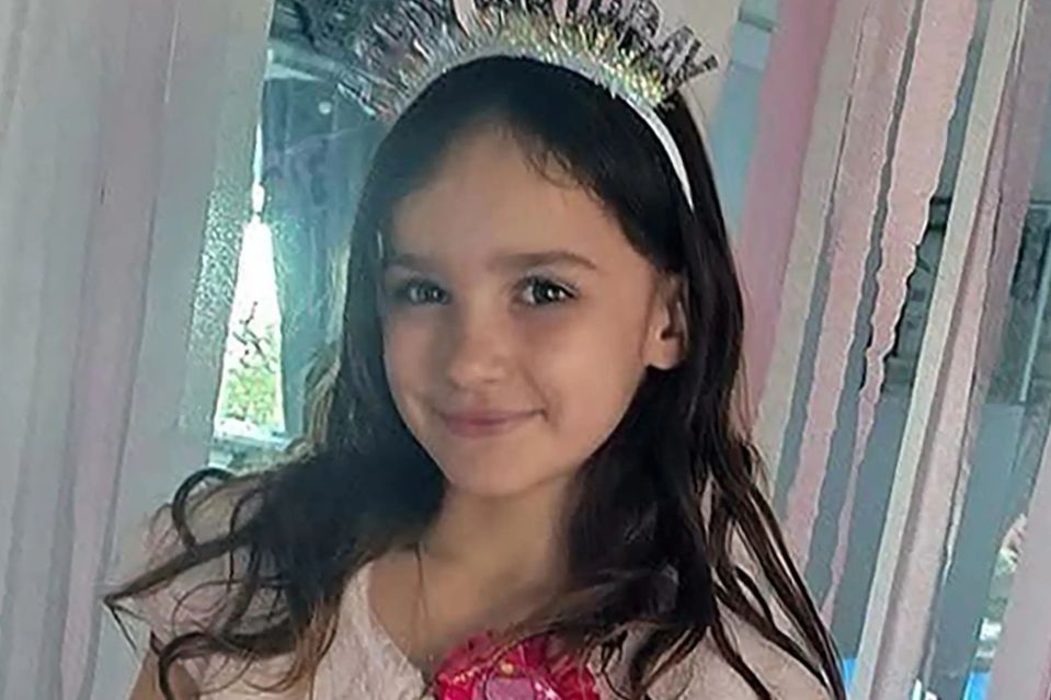 An image collage containing 1 images, Image 1 shows Aria Thorpe, a nine-year-old girl, wearing a "Happy Birthday" headband and a pink rosette badge, smiling at the camera