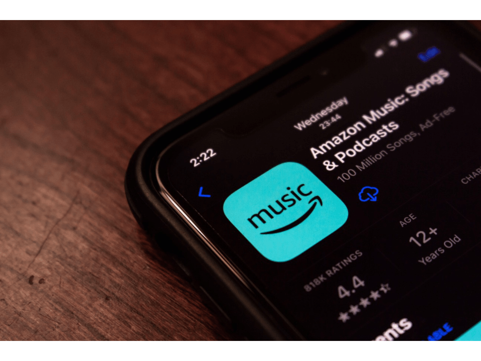A smartphone screen displaying the Amazon Music: Songs & Podcasts app page, showing 100 million songs, ad-free, 818K ratings, 4.4 stars, and age 12+.