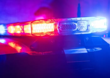 Red and blue lights flash on top of a police car.