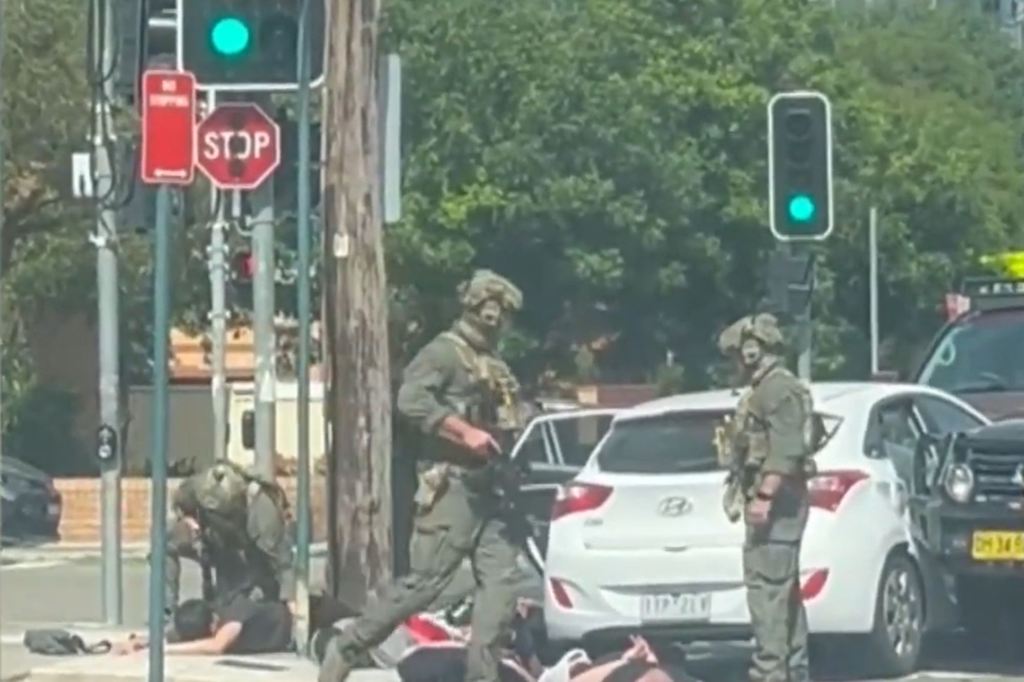 An image collage containing 1 images, Image 1 shows Armed officers in tactical gear on a city street, with one officer attending to a person on the ground